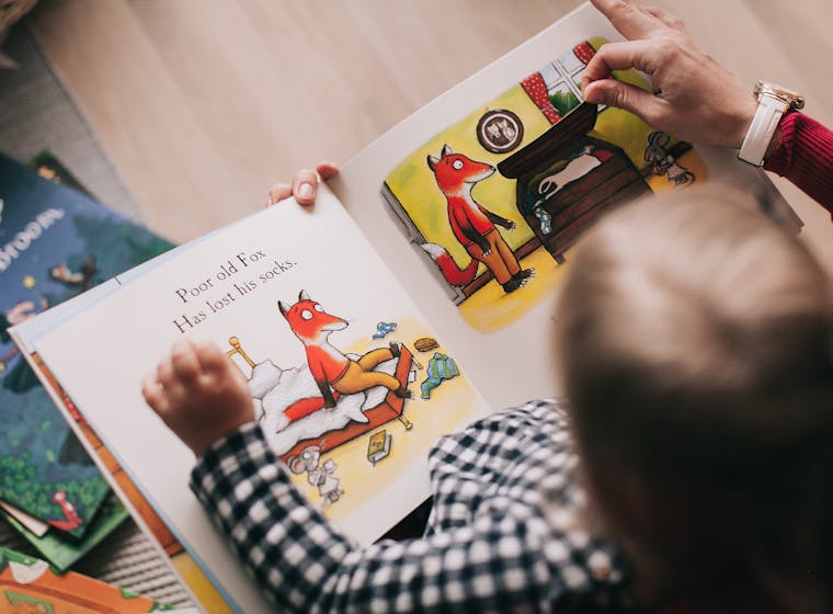 A parent and child reading an illustrated storybook together