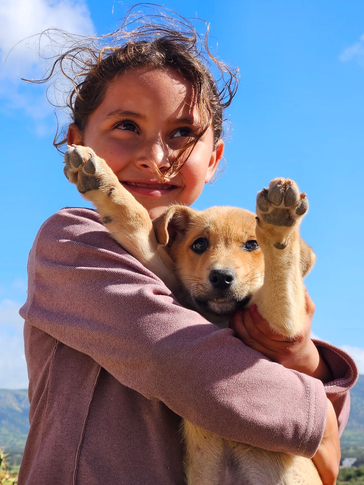A girl hugging her puppy outdoors
